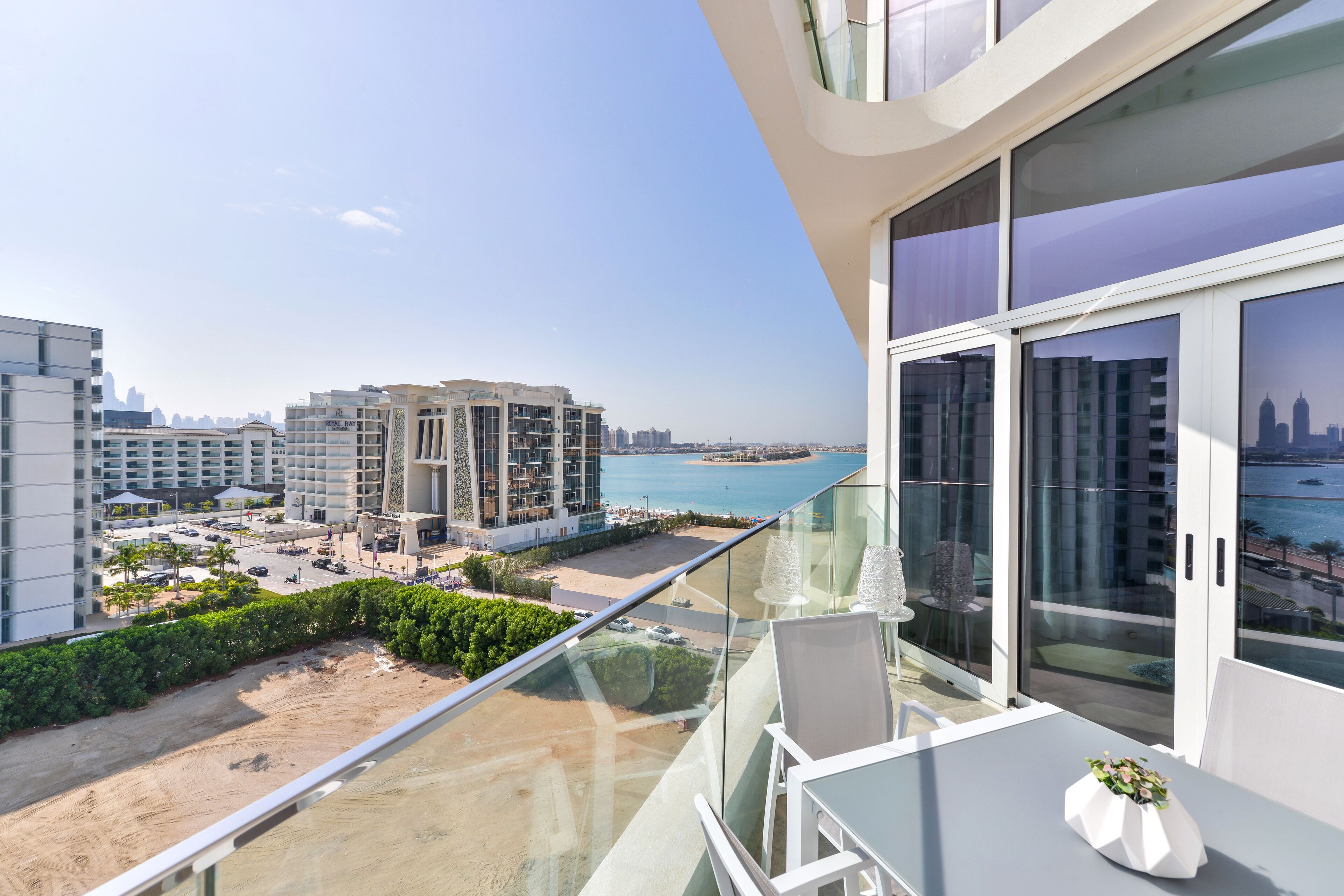 A balcony with a glass railing overlooking a beach and cityscape.