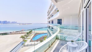 A high-rise hotel with a glass balustrade overlooking a beach and a pool.