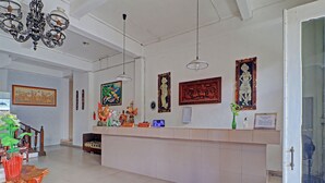 A hotel reception area with a counter, decorative items, and artwork on the walls. - Super OYO 91870 Warna Kedaton (Denpasar)