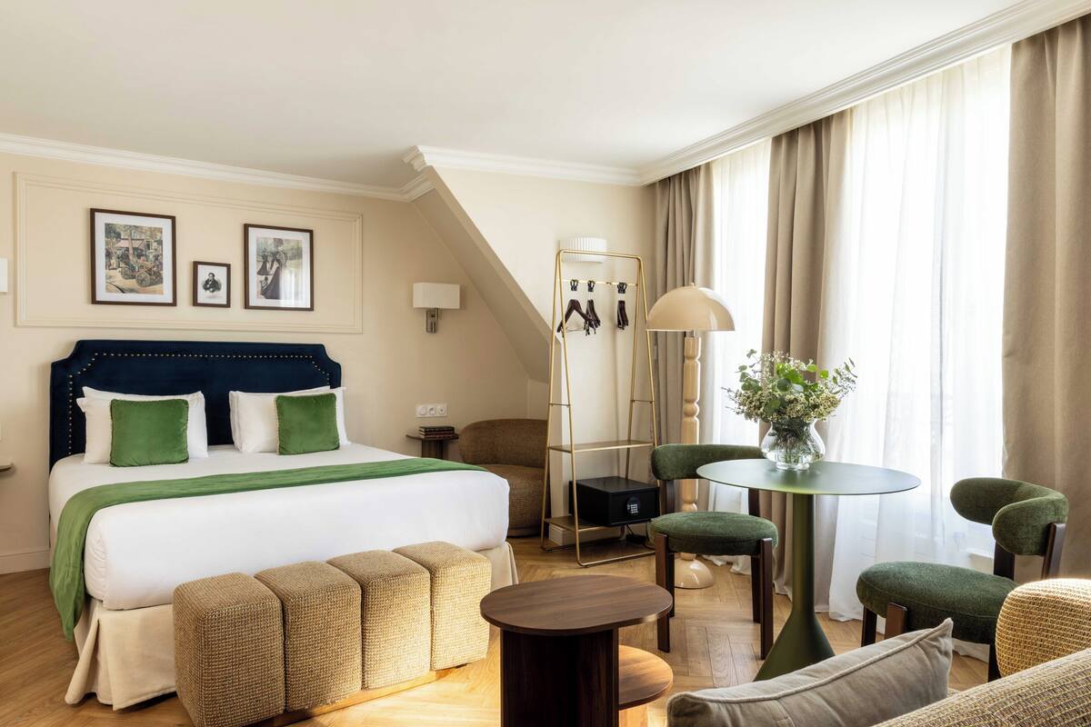 A hotel room with a bed, a desk, a chair, and a table.