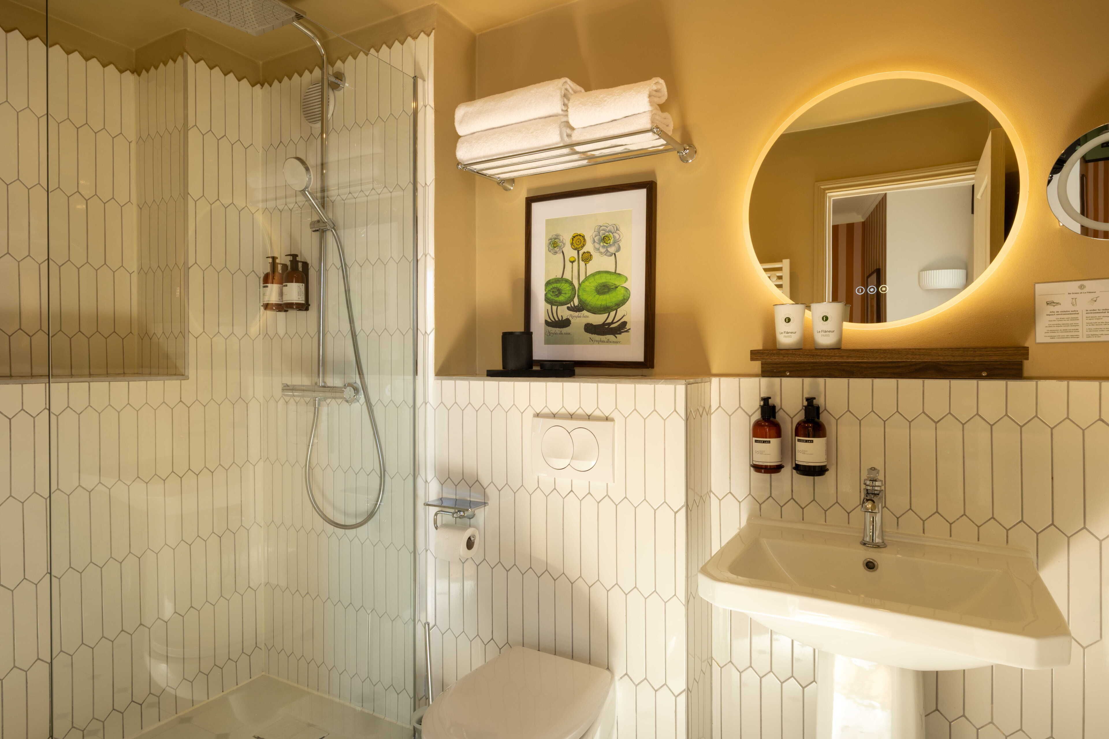 Un baño con ducha, inodoro, lavabo y un cuadro enmarcado sobre el espejo.