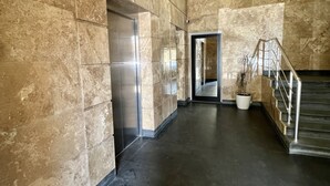 A spacious hallway with marble walls and a modern elevator. - Cozy 1-Bedroom Apartment in the Heart of Yerevan by Sweet Home (Yerevan)