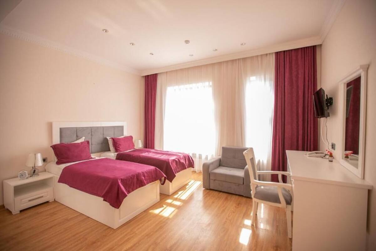Habitación de hotel con dos camas, un escritorio, una silla y un televisor.