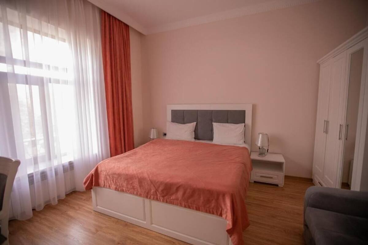 Un dormitorio con cama, mesitas de noche, una silla y un armario.