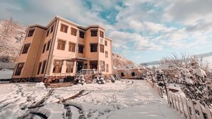 Un edificio a più piani con facciata simmetrica, un ingresso centrale e un paesaggio innevato.