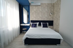 Una habitación de hotel moderna con una cama grande, un escritorio, una silla y un espejo.