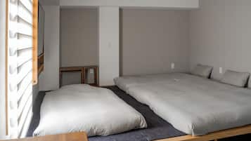 Una habitación pequeña con dos camas, un banco de madera y un radiador fijado a la pared.