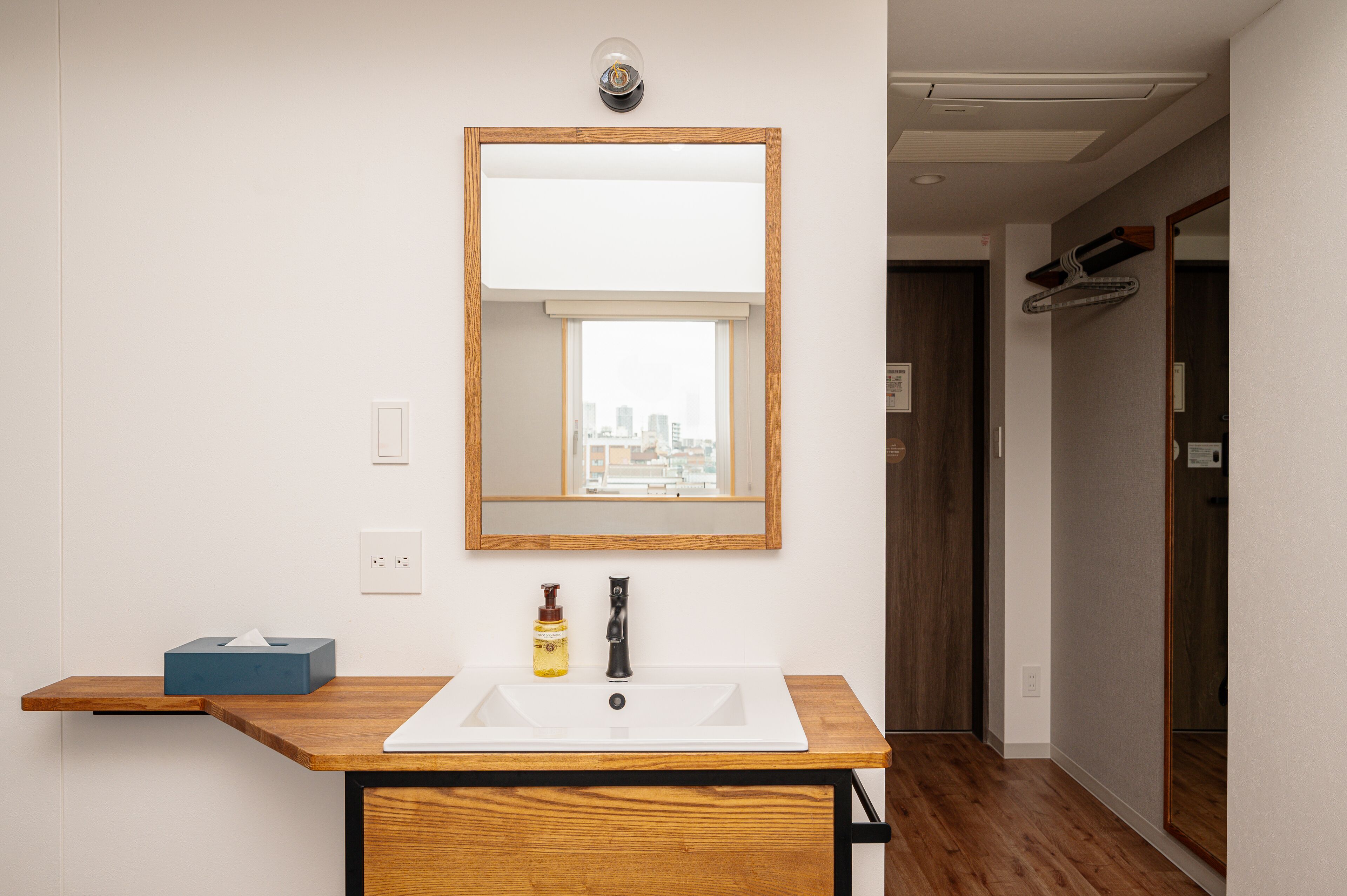 Un baño moderno con tocador de madera, un espejo grande y ventana con vista a la ciudad.