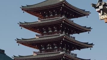 Una pagoda tradicional de varios niveles con un estanque dorado, rodeada de otras construcciones.