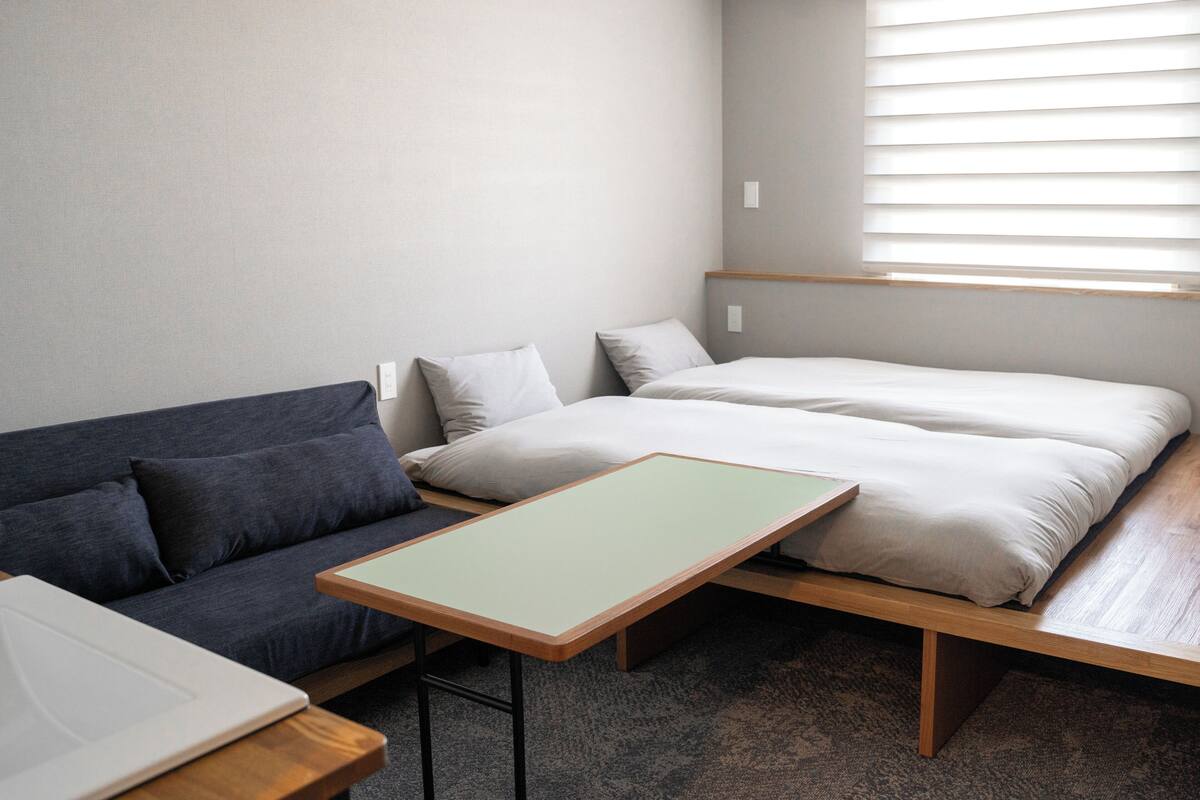 A compact room with a bed, a sofa, and a small table.