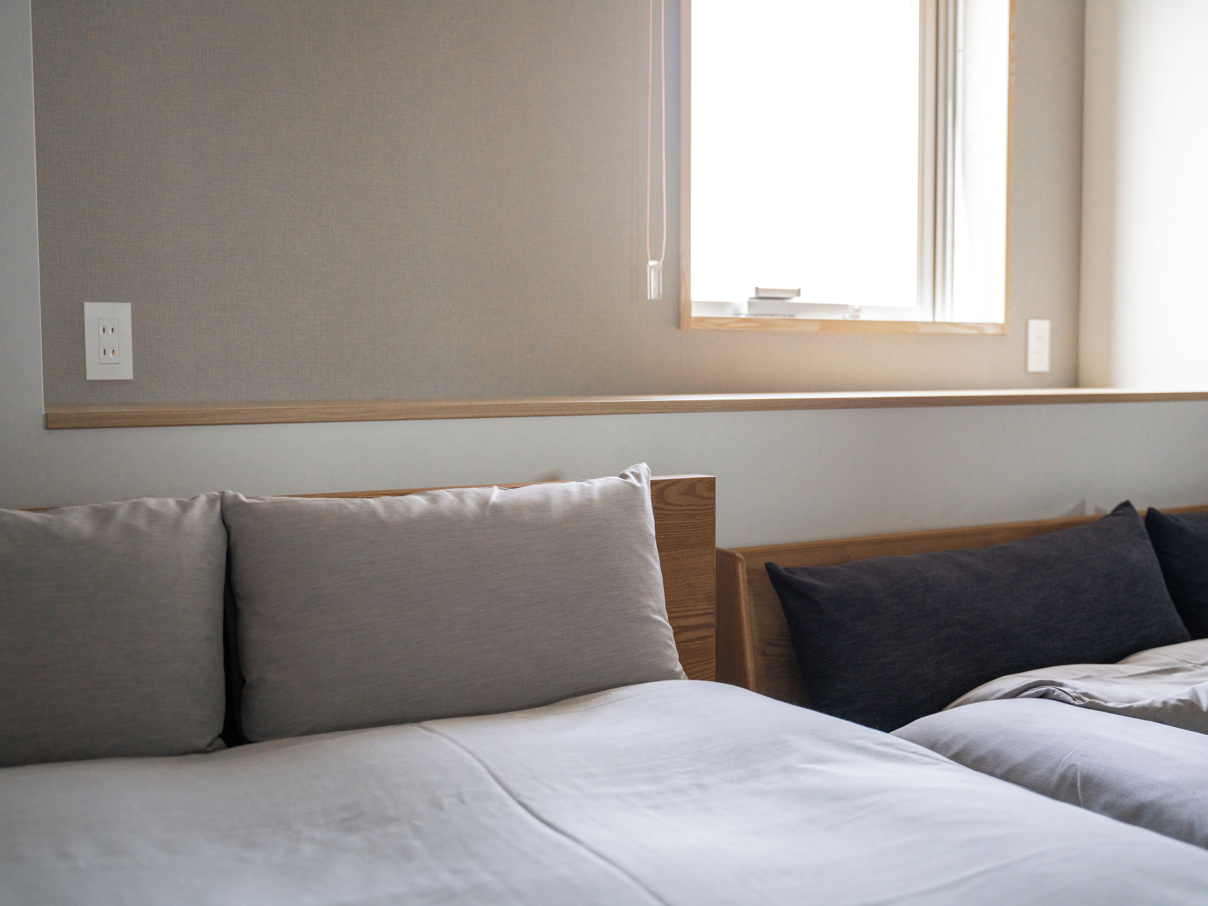 A bedroom with two beds, a window, and a wall socket.
