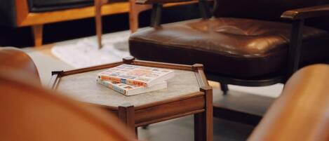 Una sala de estar acogedora con un sillón de cuero, una mesita de centro de madera con un libro y una mesita auxiliar blanca.