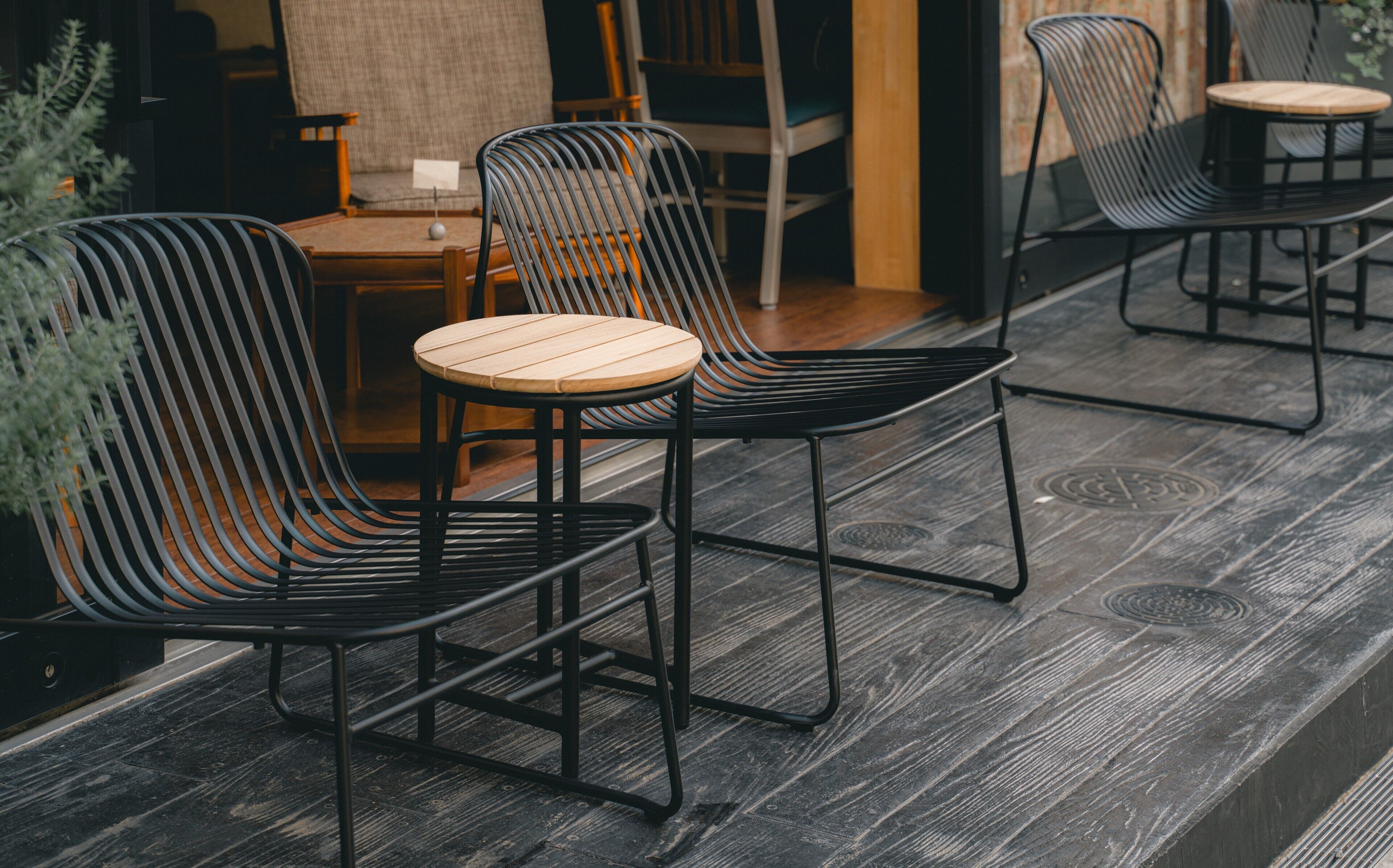 A seating area with black metal chairs and wooden tables, featuring a rustic wooden floor.