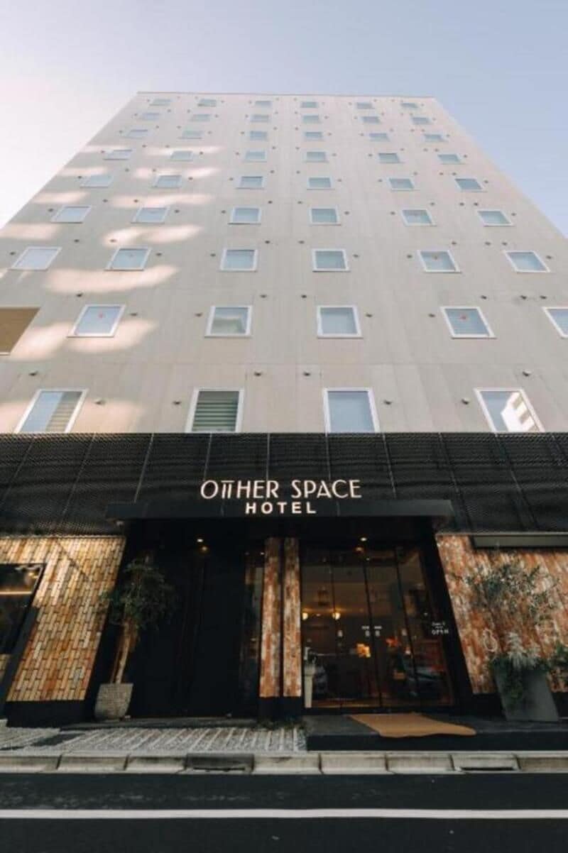 Un hotel anomenat 'Other Space Hotel' amb una façana moderna, grans finestres i un portal destacat.