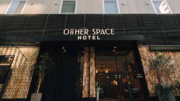 Un hotel anomenat 'Other Space Hotel' amb una façana moderna, grans finestres i un portal destacat.