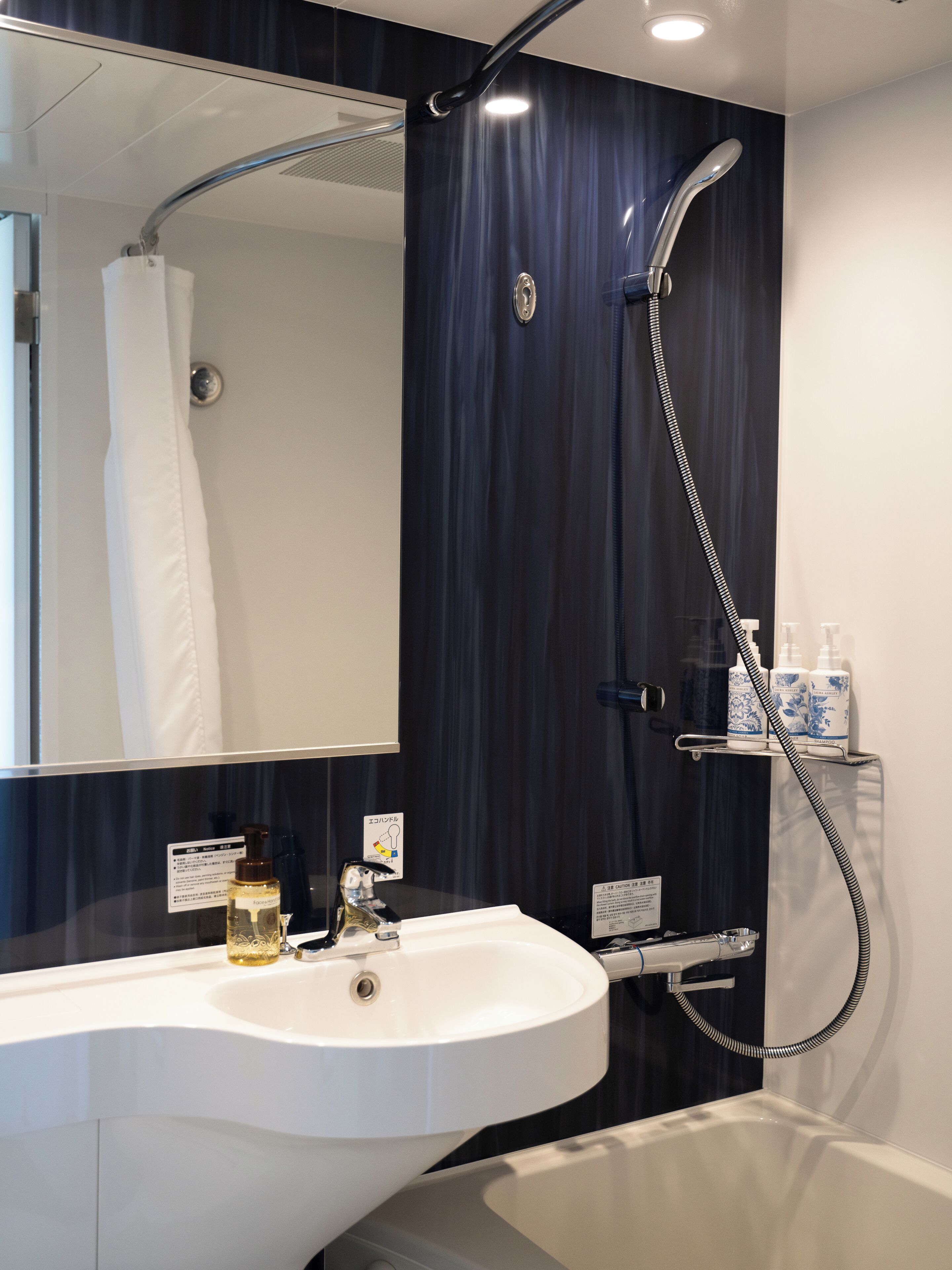 A modern bathroom with a white sink, a mirror, a shower, and a bathtub.