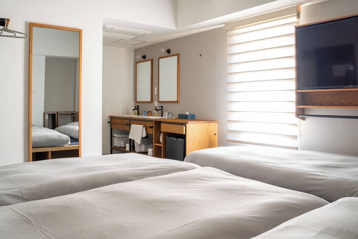 A hotel room with two beds, a wooden dresser, a mirror, and a television.