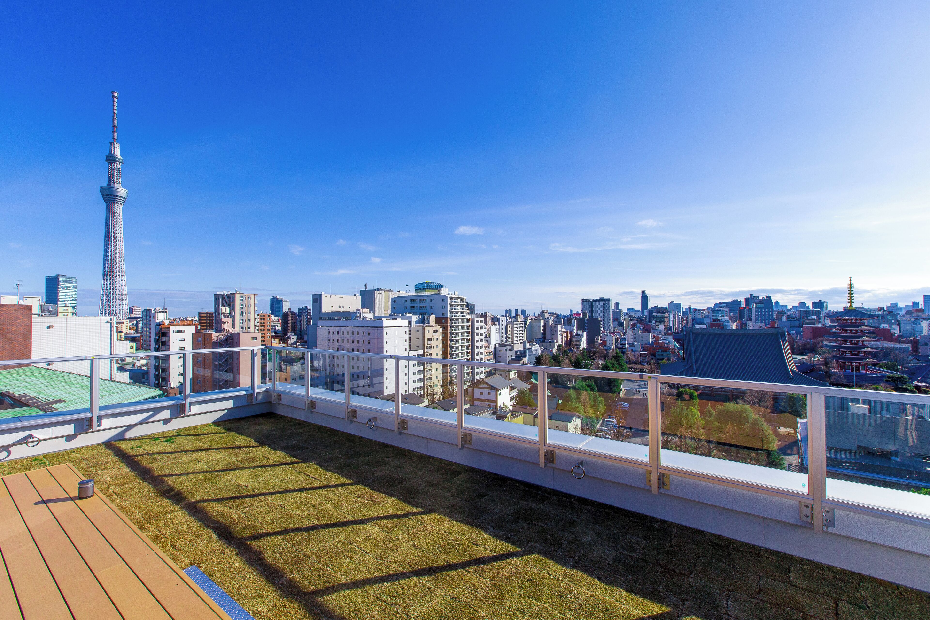 A rooftop terrace with a city view, including a prominent tower and various buildings.