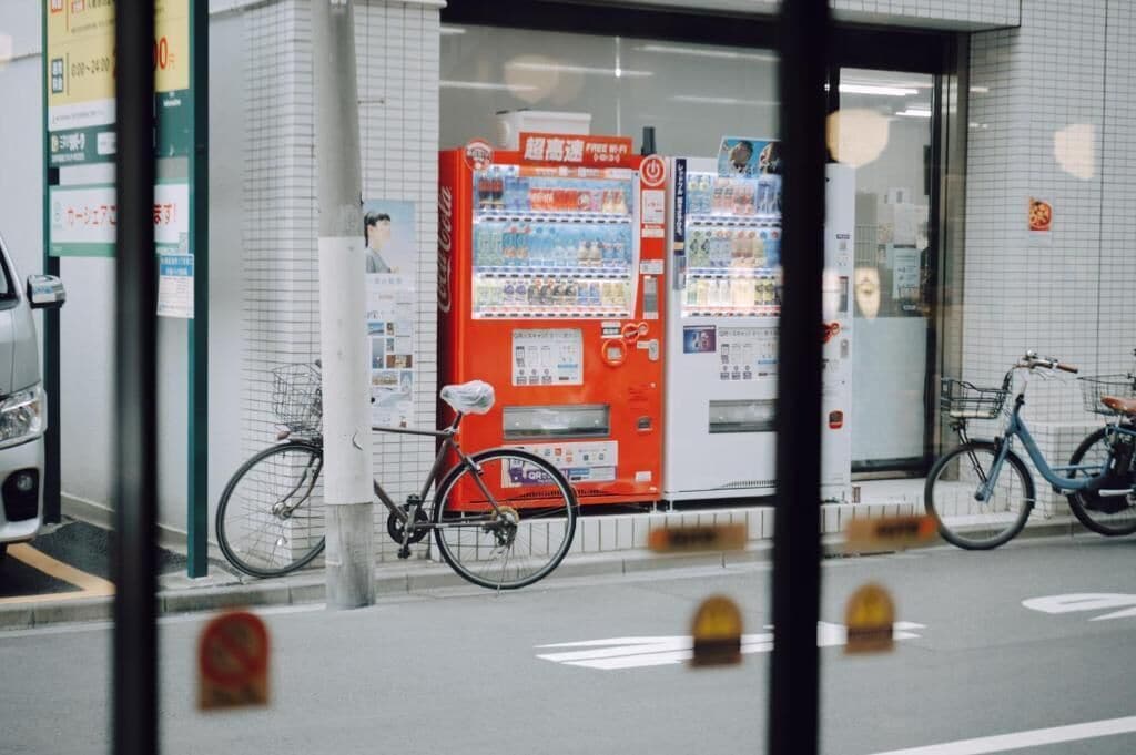 Un distributeur automatique avec un vélo garé à côté, et un vélo garé devant un immeuble.