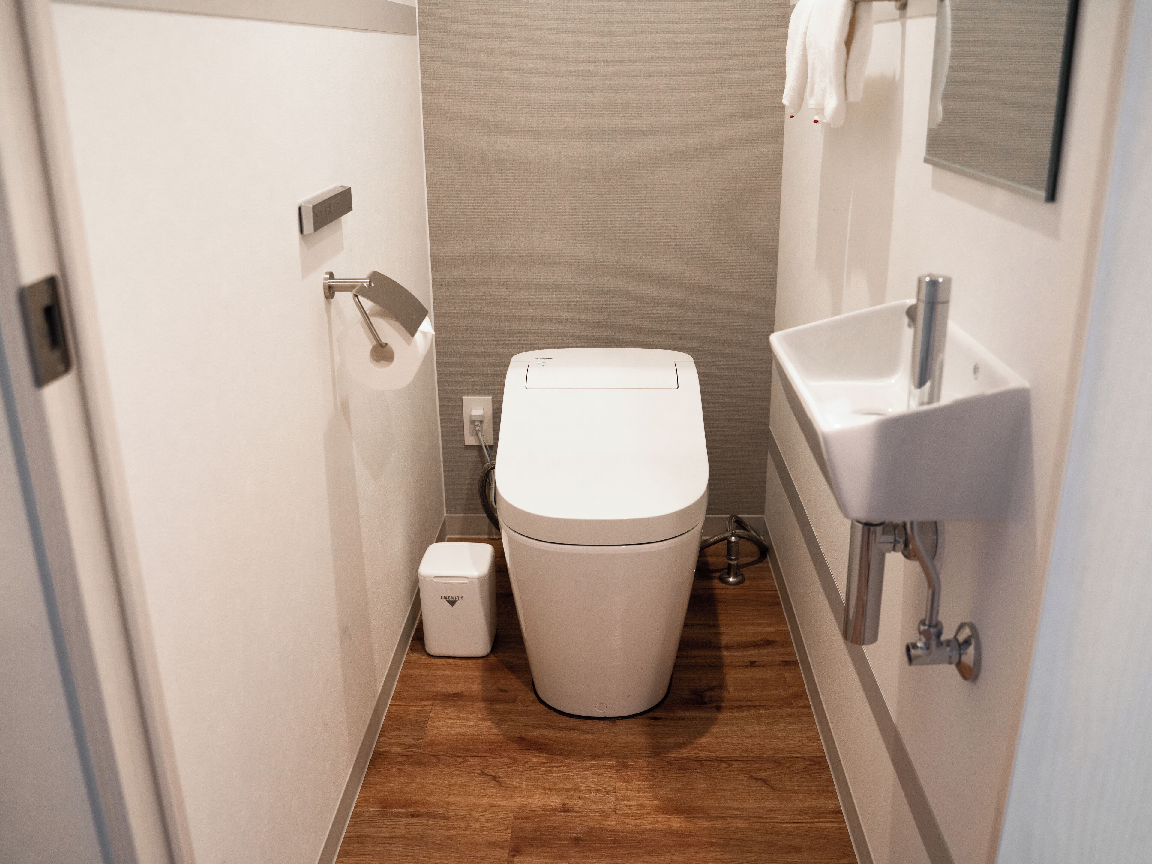 A compact bathroom with a toilet, a small trash bin, and a sink.