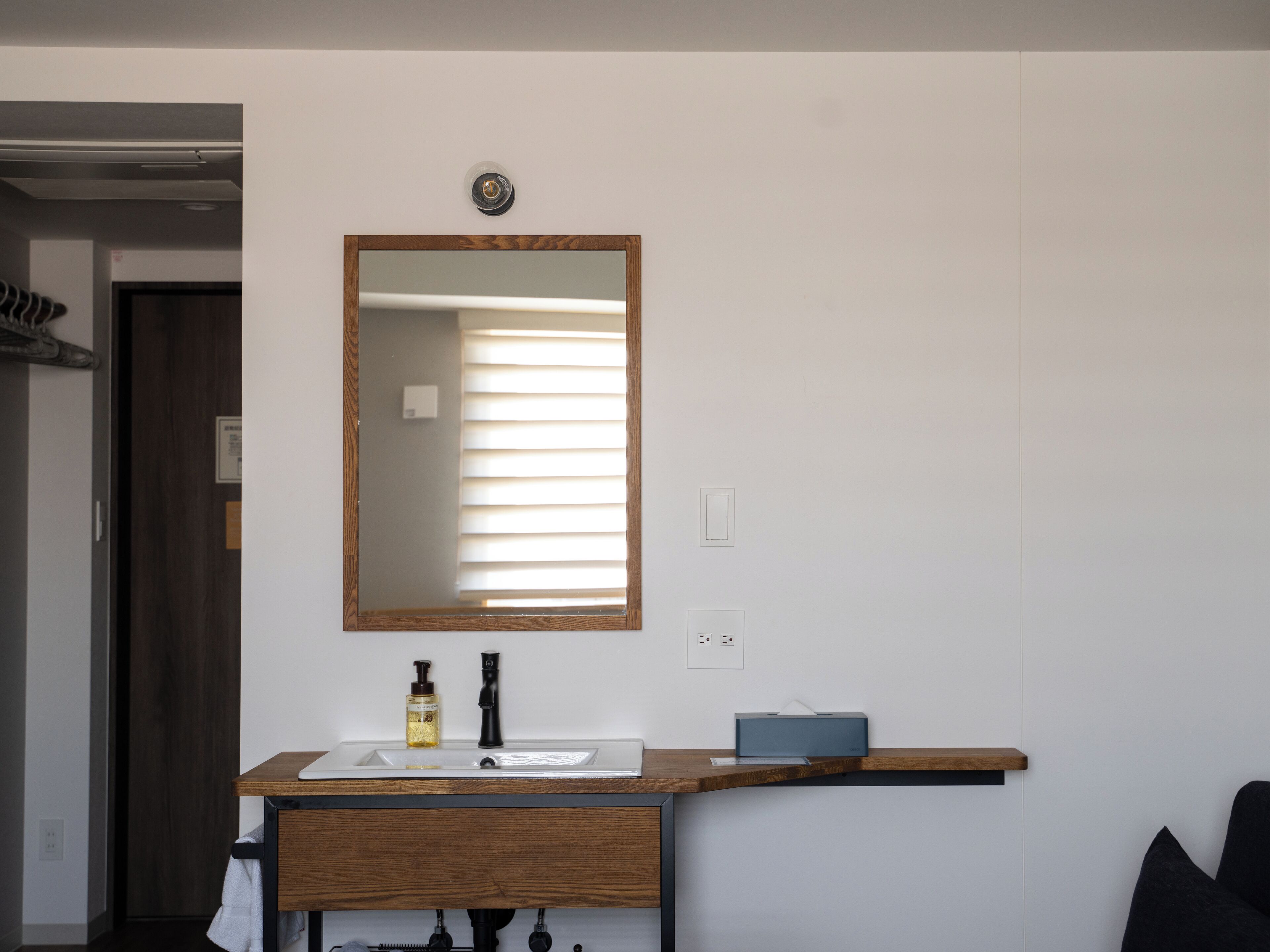 A bathroom with a wooden vanity, a mirror, a sink, a towel, and a towel rack.