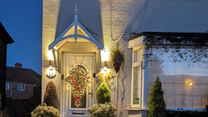 A house with a well-lit front door, a small porch, and a gravel driveway. - Tropical Garden Oasis (Birmingham)