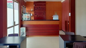 A reception area with a wooden counter, a reception desk, and a wall clock. - Hotel O Kost Orange Syariah (Makassar)