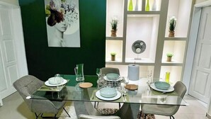 Un espace repas moderne avec une table en verre, des chaises grises et un tapis blanc.