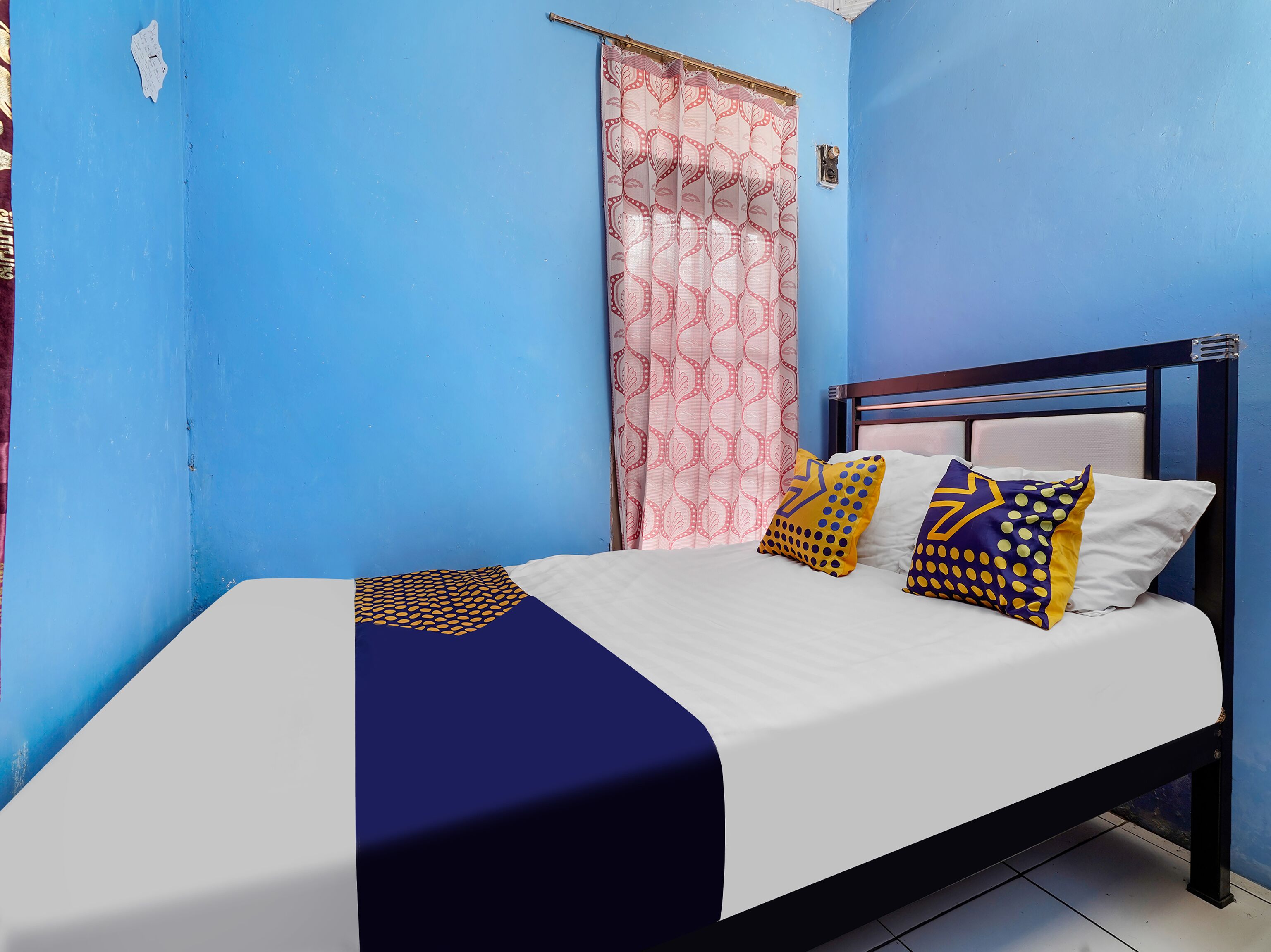 A bed with a white and navy blue bedspread, two patterned pillows, and a wooden headboard.