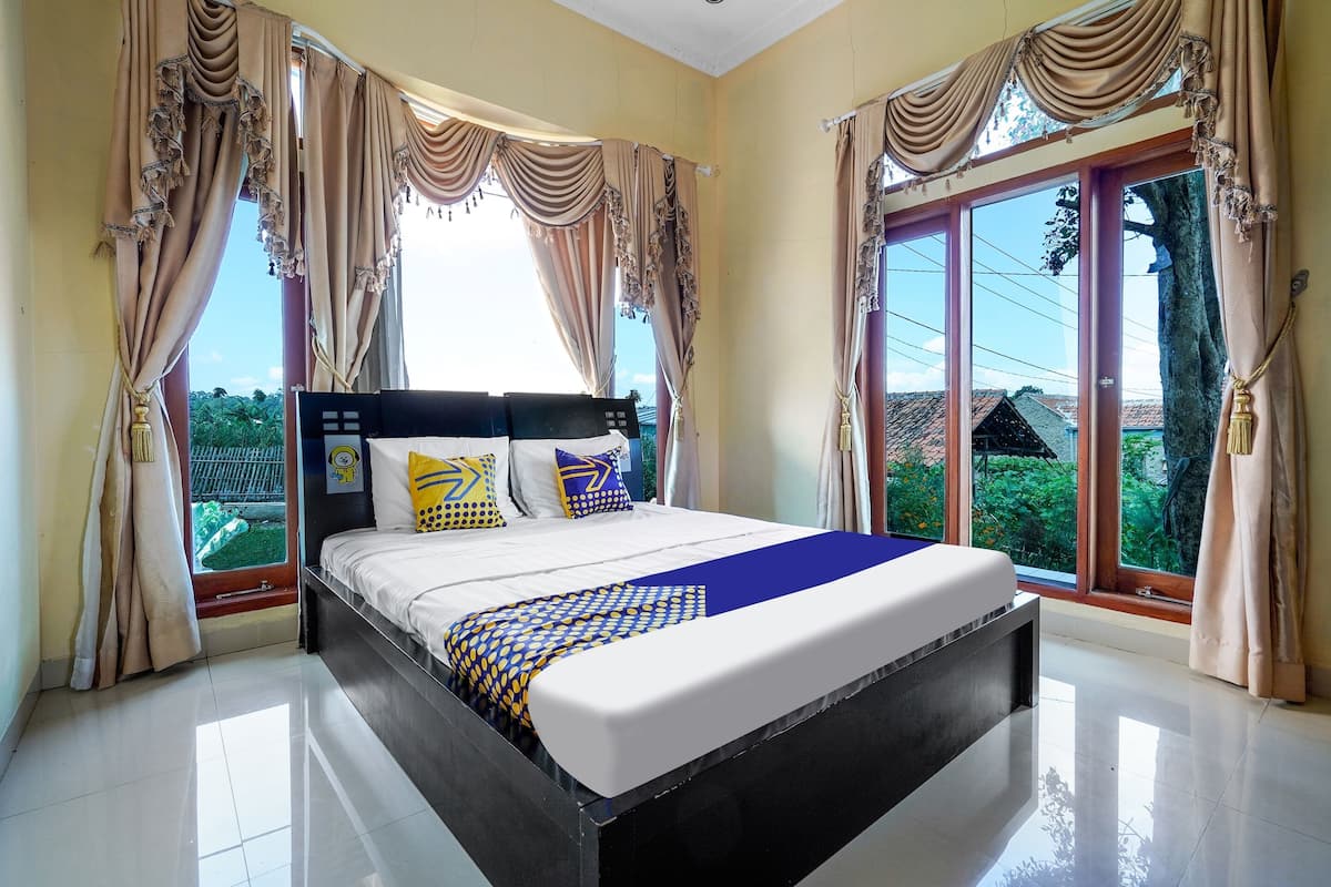 A bed with a headboard, curtains, and a view of greenery outside.