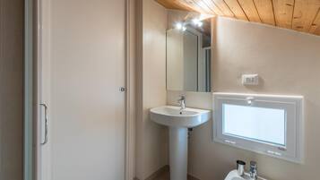 Ett badrum med ett handfat på piedestal, en spegel och en toalett.