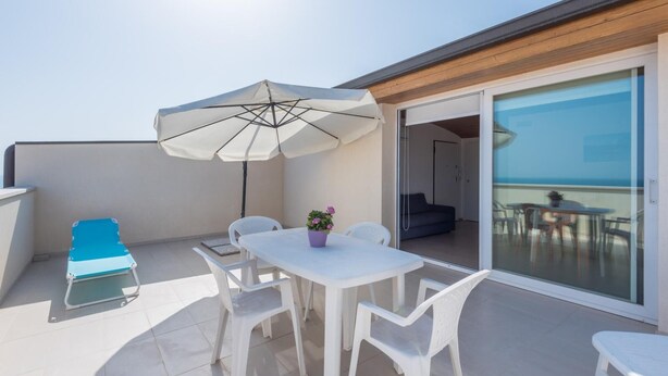 A balcony with a white table, chairs, a blue lounge chair, and a large umbrella. - Splendid attic with large veranda. (RAGUSA)