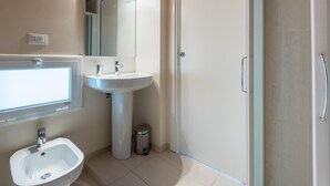 Une salle de bain moderne avec un lavabo sur colonne, un miroir et un espace douche.