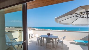Un balcon avec une table, des chaises et une vue sur la plage.