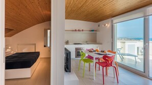 Un appartement moderne avec une chambre en mezzanine, une cuisine avec vue et un coin repas agrémenté de chaises colorées.