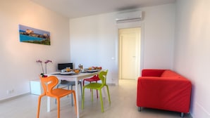 A modern living room with a dining area, featuring a red sofa, colorful chairs, and a painting on the wall. - Modern and elegant apartment (RAGUSA)