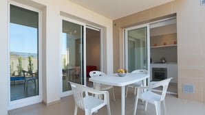 A modern kitchen with white cabinets and a dining area with a white table and chairs. - Modern and elegant apartment (RAGUSA)