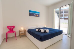 Un dormitorio moderno con cama, mesita de noche, silla y un cuadro en la pared.