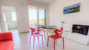 A bright living room with a dining area, a TV, and a painting of a coastal scene. - Amazing Seaview Apartment with two bedroom (RAGUSA)