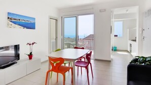 A modern living room with a dining area, large windows, and a view of the sea. - Amazing Seaview Apartment with two bedroom (RAGUSA)
