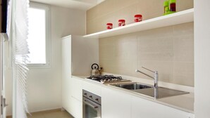 A modern kitchen with a gas stove, stainless steel sink, and a window with blinds. - Amazing Seaview Apartment with two bedroom (RAGUSA)