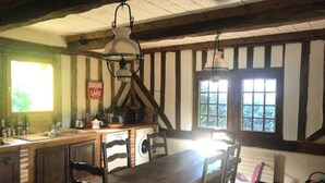 Una cocina rústica con vigas de madera, una amplia mesa de madera y una lámpara colgante.