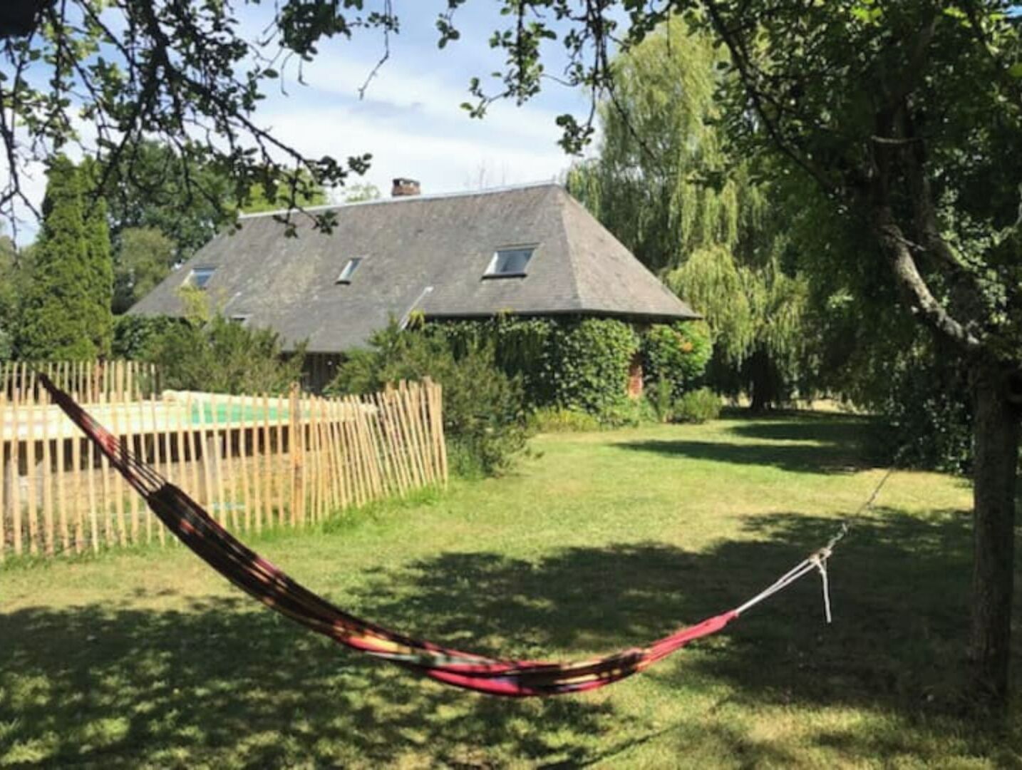 A hammock in a grassy yard with a house in the background.