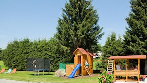 A playground with a slide, a small wooden structure, and a bench. - Pension Wiesengrund (Neuschoenau)
