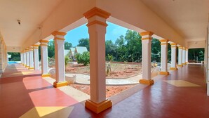 A covered outdoor area with a series of columns and a tiled floor. - Auro Sunrise Resort (Vanur)