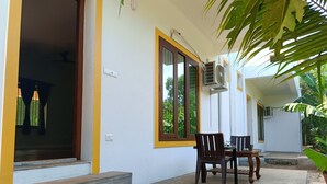 A building with a covered patio, a table and chairs, and a staircase leading to an entrance. - Auro Sunrise Resort (Vanur)