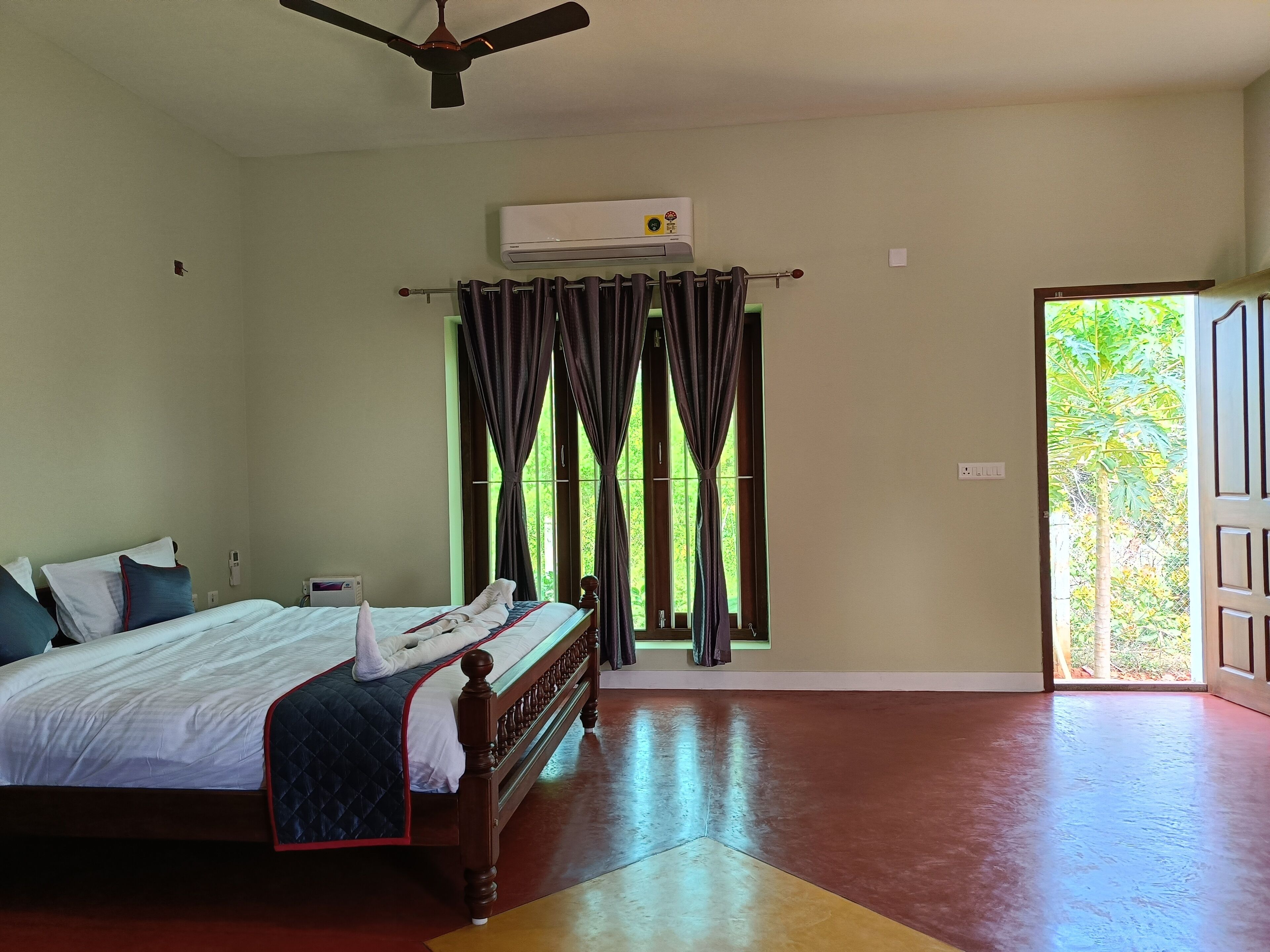 A bedroom with a bed, an air conditioning unit, a ceiling fan, and a window with curtains.
