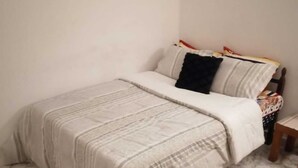A bedroom with a bed, a nightstand, a chair, and a small table. - Lovely spacious and quiet small budget Room is located in the Center of AbuDhabi (AbuDhabi)