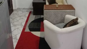 A small, compact room with a white sofa, a black side table, and a patterned rug. - Lovely spacious and quiet small budget Room is located in the Center of AbuDhabi (AbuDhabi)