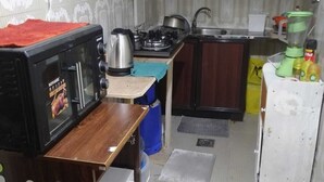 A compact kitchen with a microwave, stove, sink, and a small refrigerator. - Lovely spacious and quiet small budget Room is located in the Center of AbuDhabi (AbuDhabi)